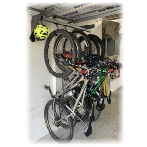 Wall mounted sliding bike storage rack under garage door rail holding five bikes and a helmet.