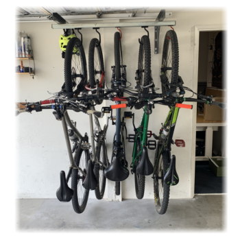Wall Mounted Sliding bike rack under garage door rail using a pair of brackets, and a 48inch Unistrut with large and standard sliding hooks, holding five bikes.