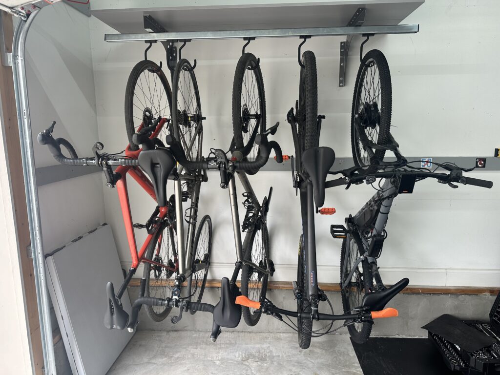 Five bikes on sliding bike rack under garage door rail.